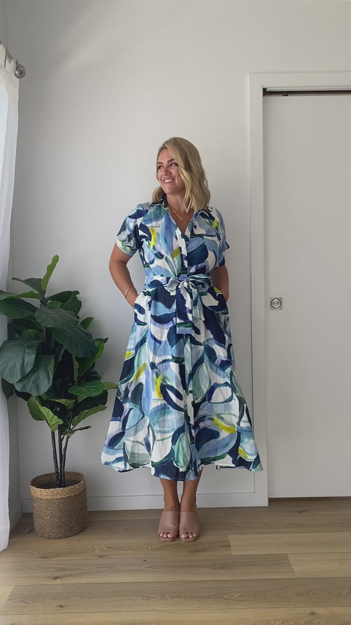 Video of a blonde model wearing a short-sleeve linen shirt dress with a blue art print